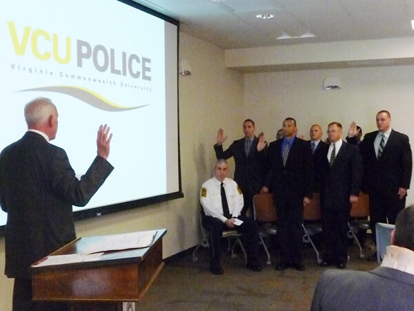 Richmond Circuit Court Clerk Bevill M. Dean, left, leads the swearing in of the recruits from the 37th Basic Academy as newly promoted Assistant Chief Christopher Preuss (seated) watches. Photo by Mike Porter, Office of Communications and Public Relations. 
