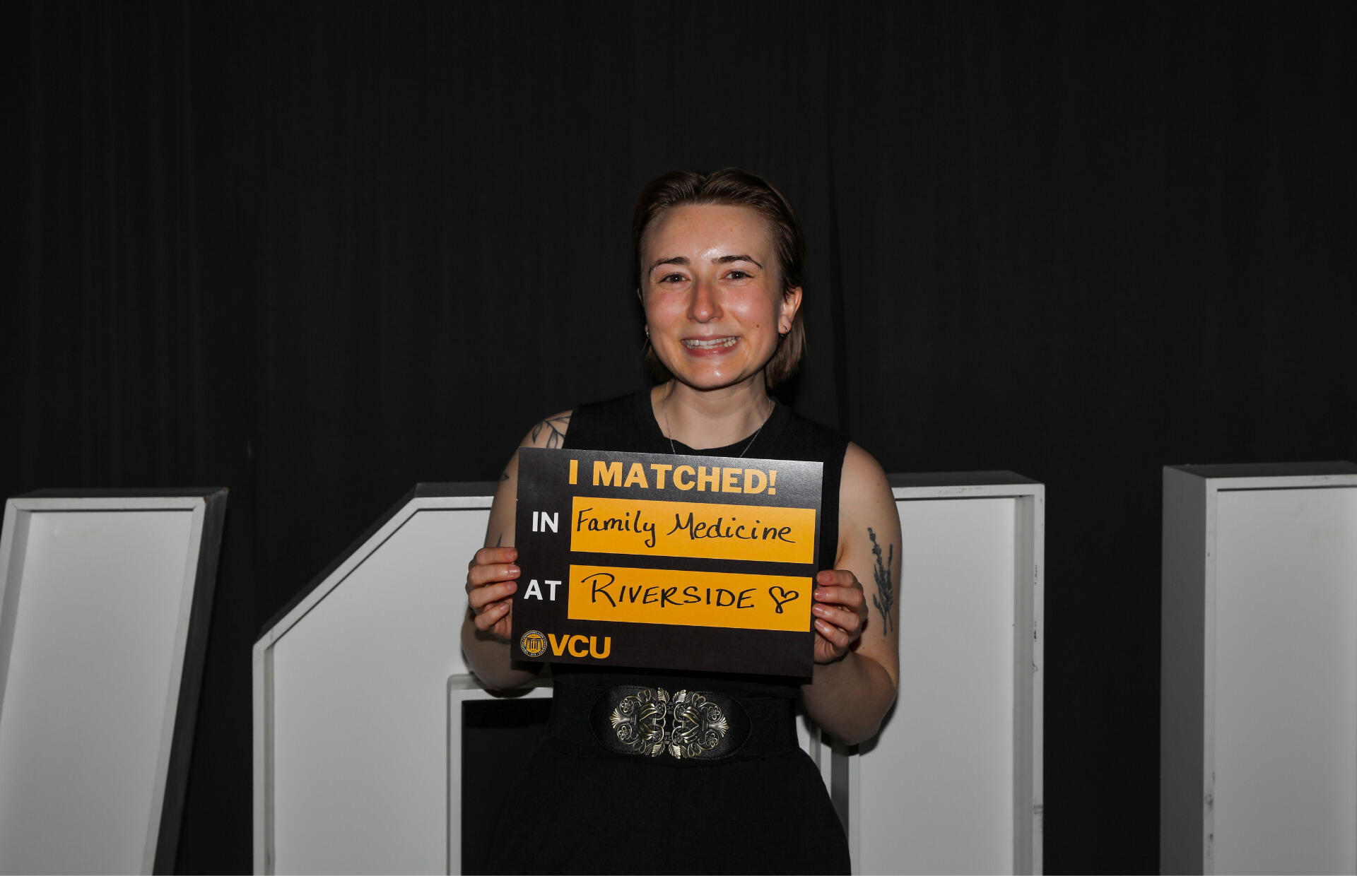 A photo of a woman holding a sign that says \"I MATCHED!\" \"IN Family Medicine\" \"AT\" \"RIVERSIDE\" 