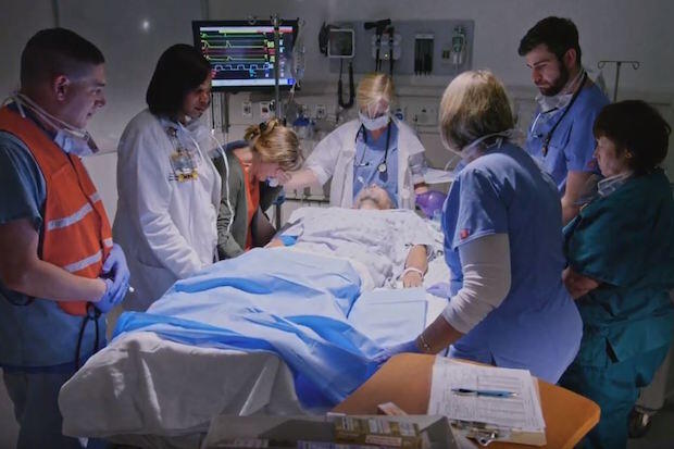 Hospital staff observe a moment of silence around the bed of a deceased patient.