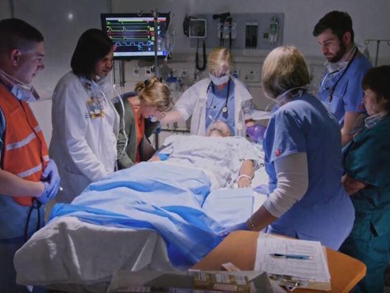 Hospital staff observe a moment of silence around the bed of a deceased patient.