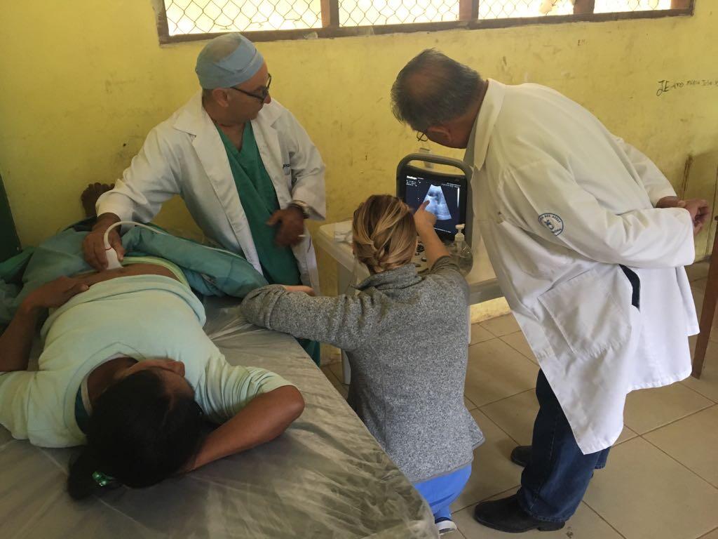 Doctors huddle around an ultrasound monitor.
