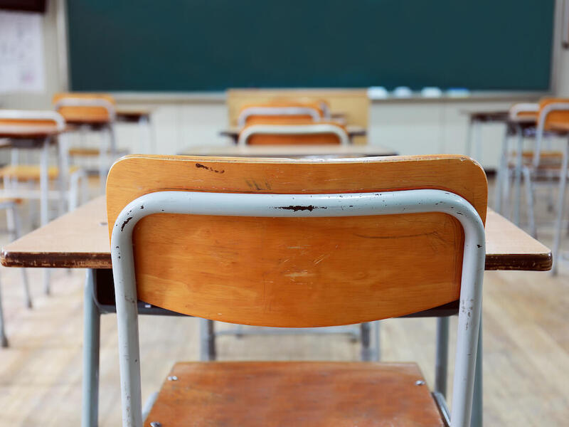 A classroom with rows of desks facing a chalkboard.