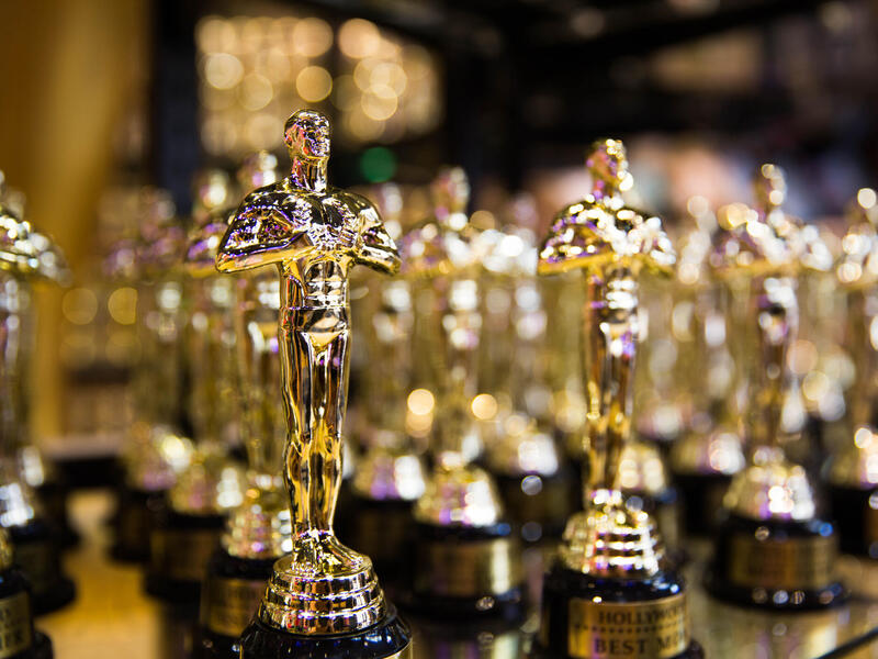 A photo of several Oscar award statues lined up. 