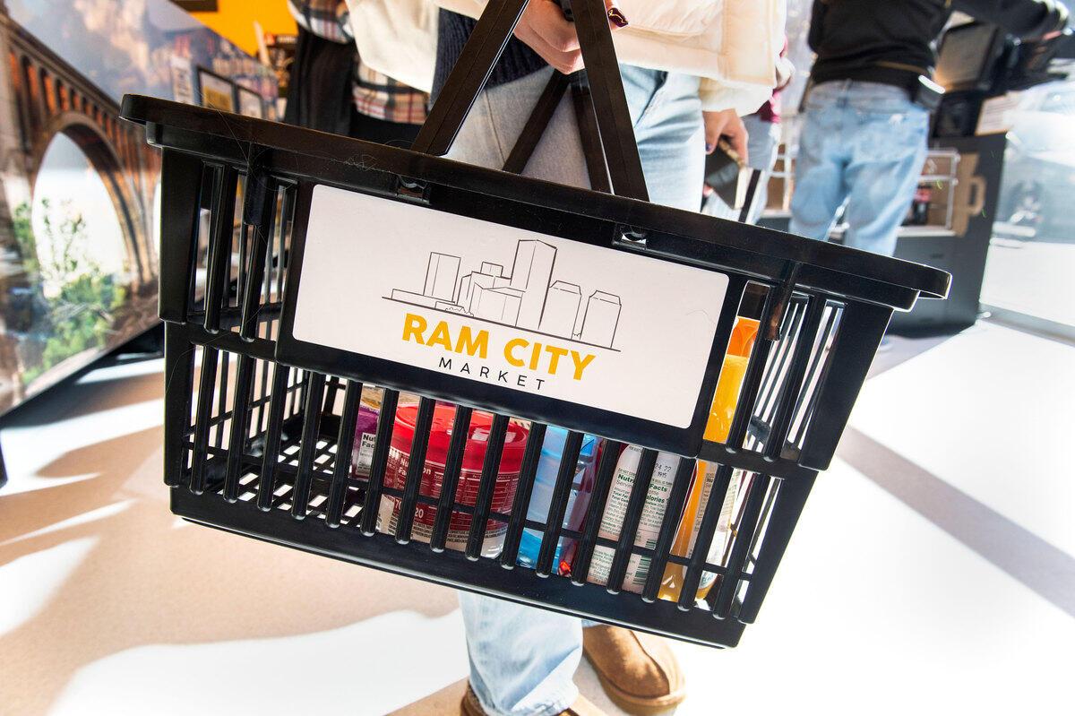 A hand basket with food it in. The hand basket has a label that reads \"RAM CITY MARKET\" on it 