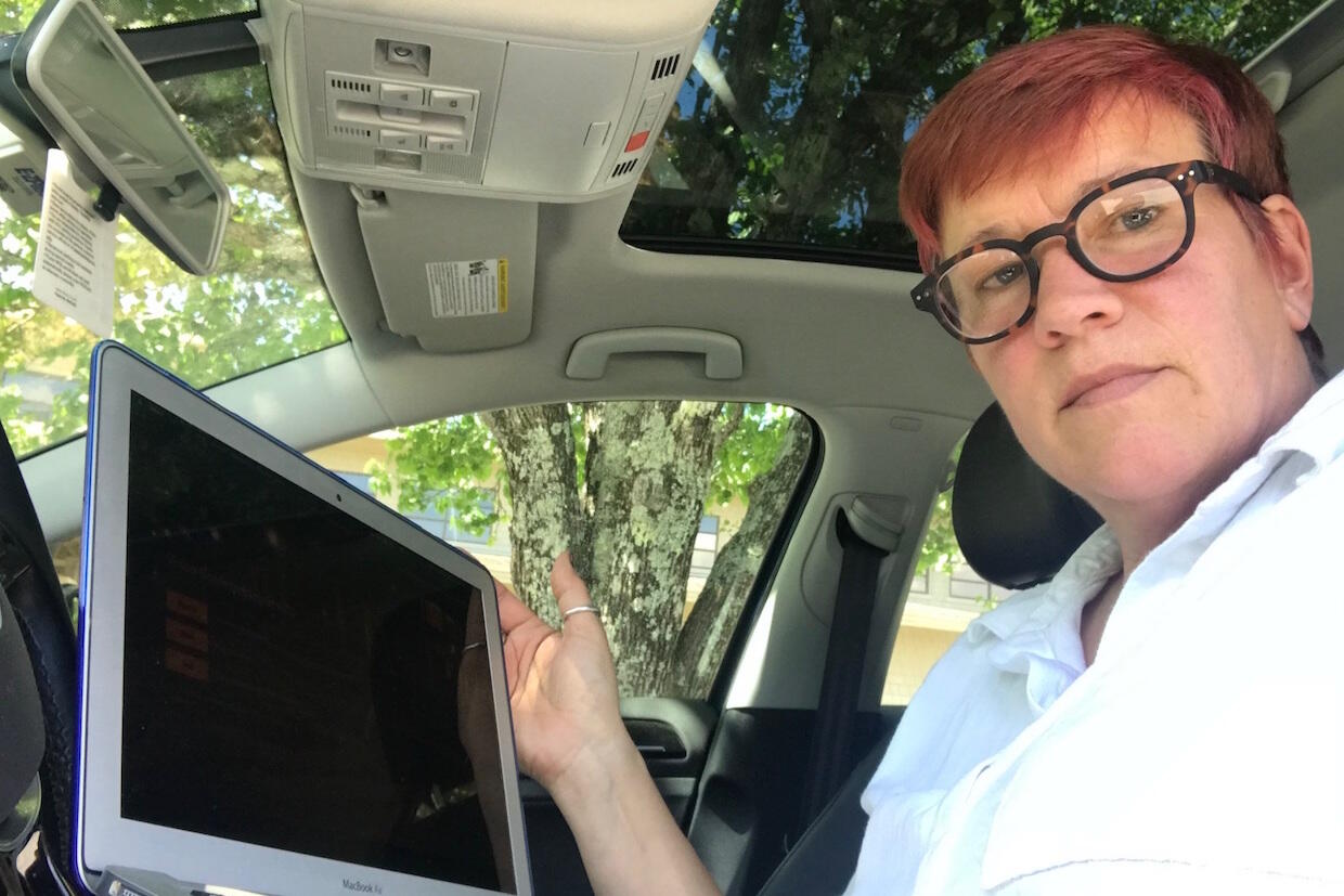 VCU instructor Jessica Lonnes sitting in her car with a laptop, teaching her class.