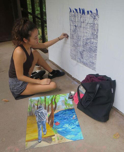 Jini Park, a student in the VCU School of the Arts, paints a mural on the Texas Beach stair tower in the James River Parks System. (Photo courtesy the James River Hikers.)