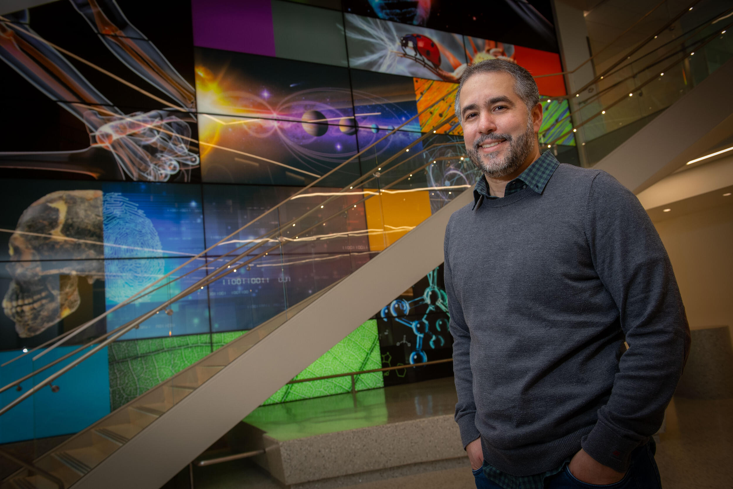 A photo of a man standing next to a staircase. 