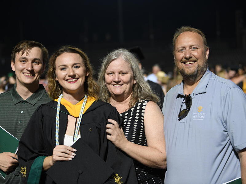 A photo of four people standing and smiling. 