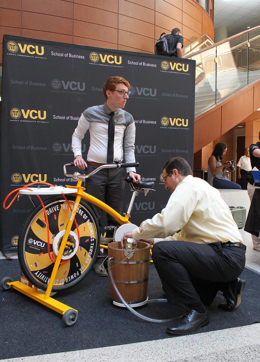 Ken Kahn, Ph.D., senior associate dean in the School of Business, (right) and Henry Winfiele from the dean's office prepare the VCU School of Business ice cream bike for another batch during the Business Organizations and Student Services Fair. The stationary bike powers an old-fashioned ice cream machine.