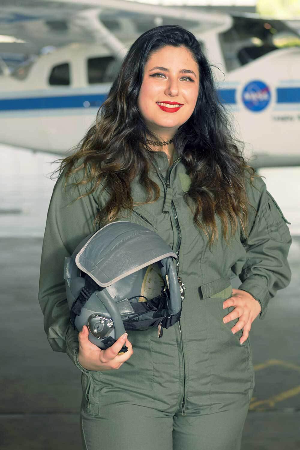 Lilly Balderson wearing a flight jumpsuit and holding a helmet.