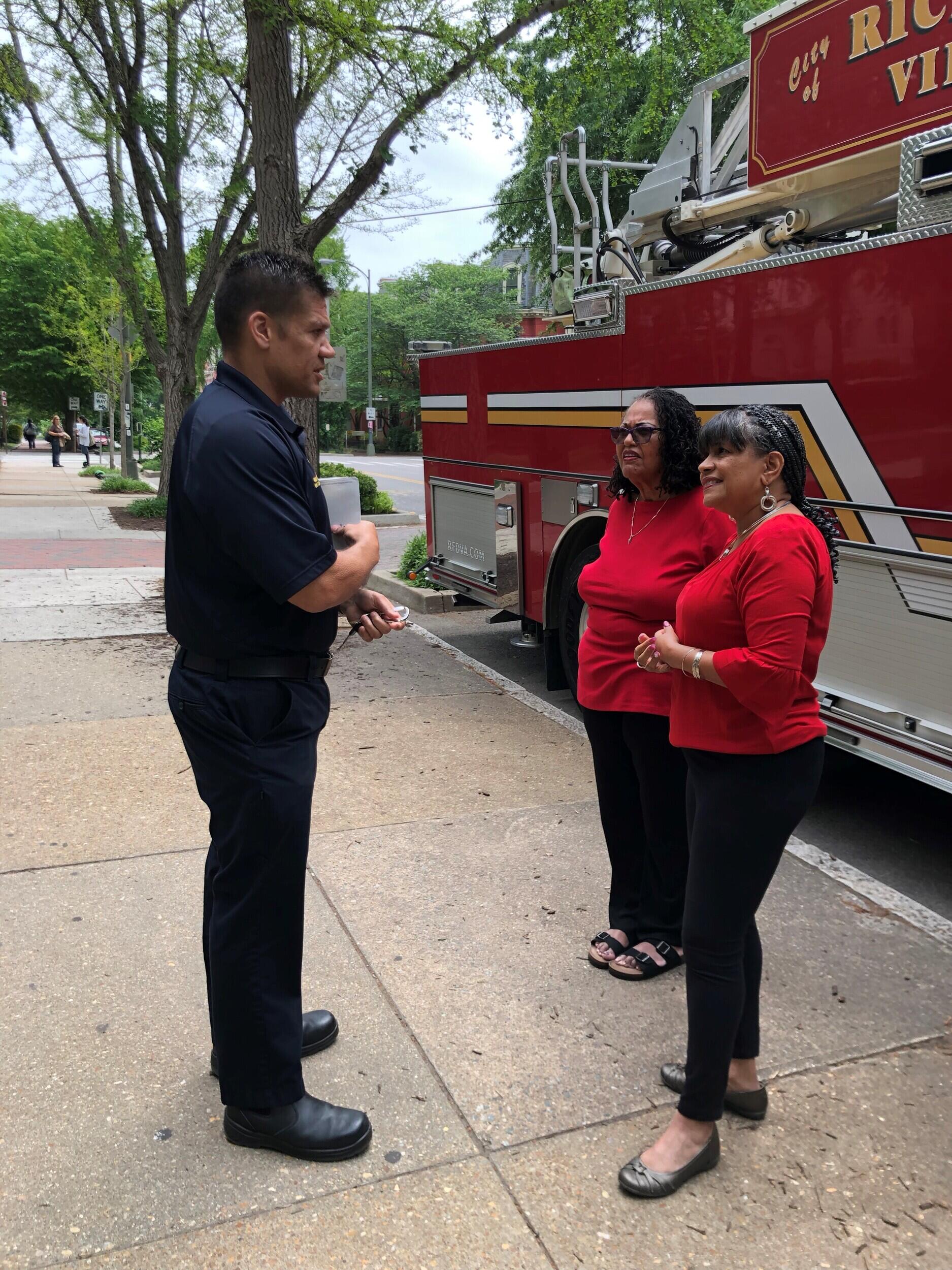 A man standing in front of two women next to a fire truck 