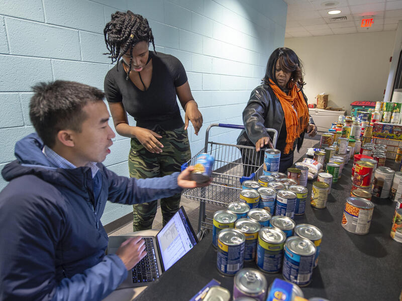 Three people sort and track donated food items.