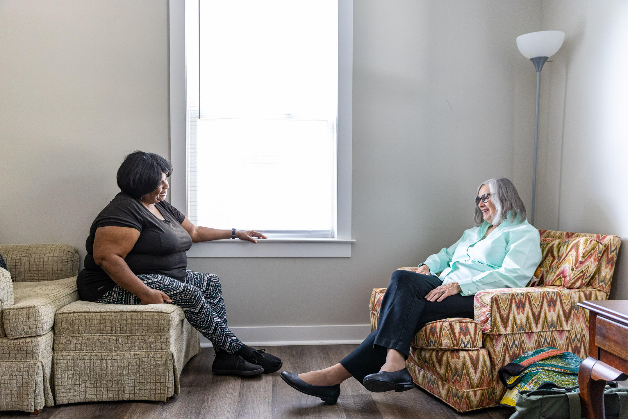A photo of two women sitting across from each other in a living room. 