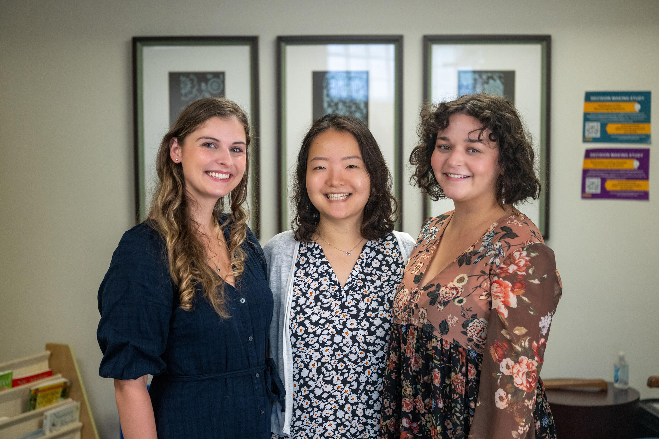 A photo of three women from the waist up smiling. 