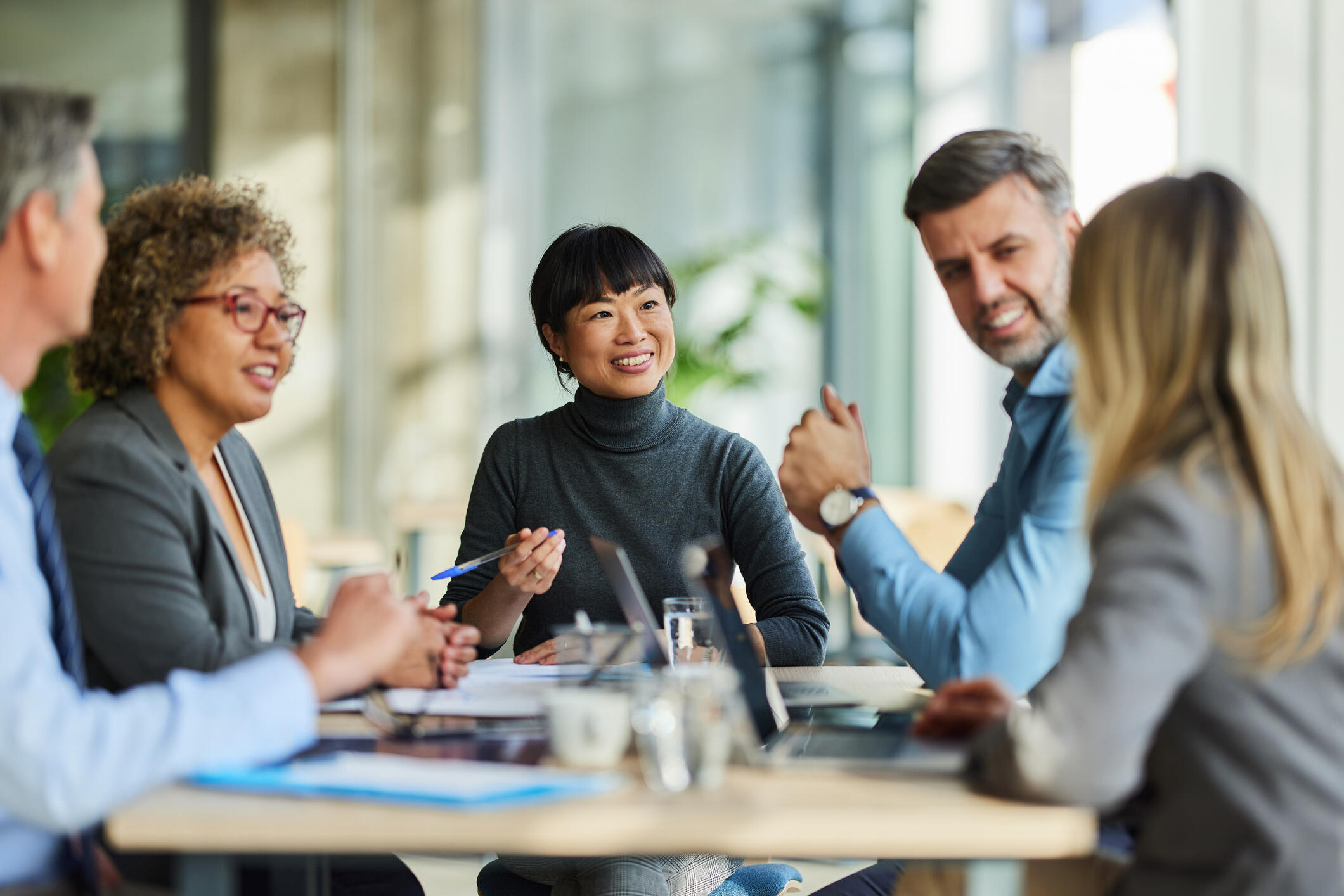 Men and women speak around a conference table, illustrating a study about the connection between emotional intelligence and being a good worker.
