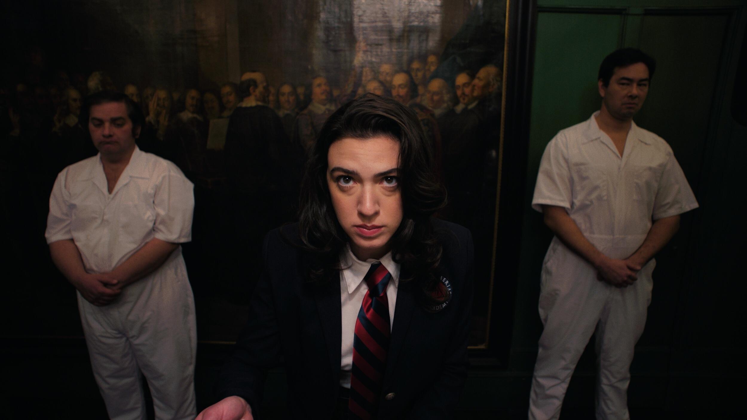 A photo of a woman in a suit and tie standing in between two people wearing all white outfits. 