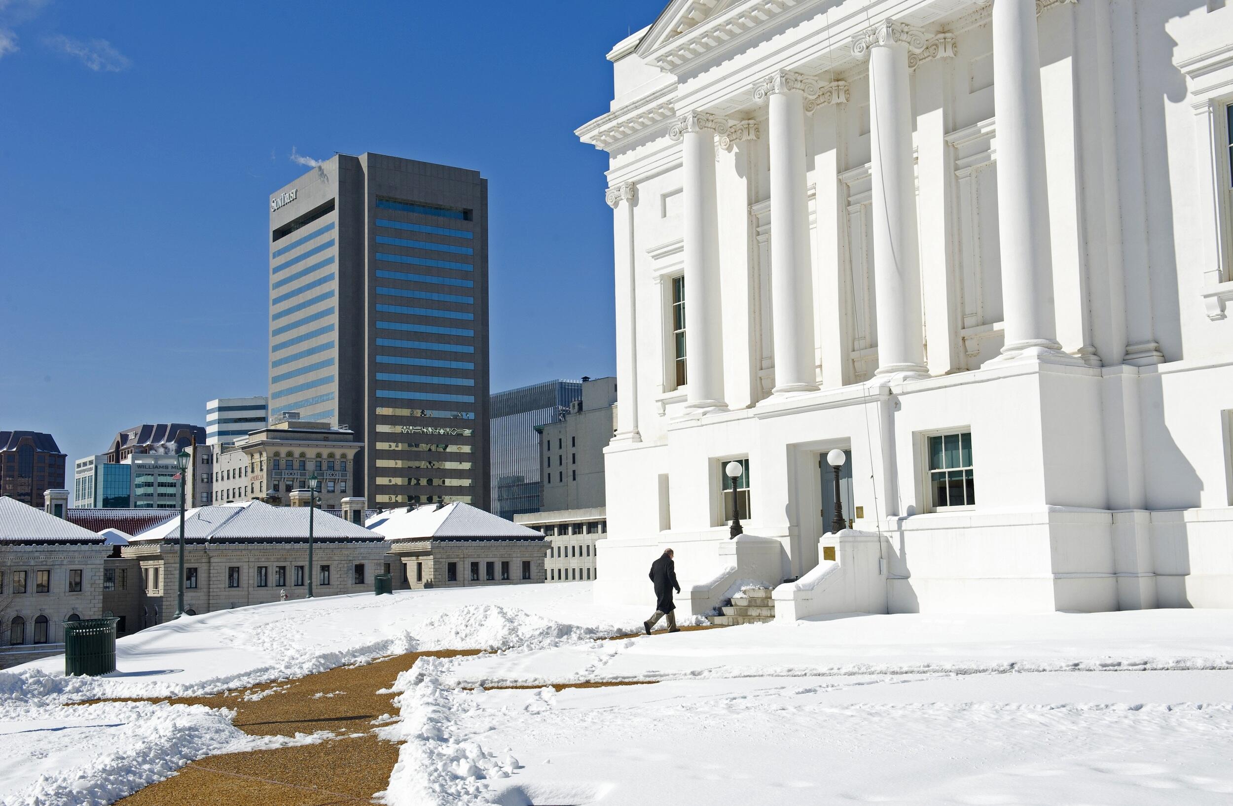 A person walking up to the Virginia State Capitol in the snow. 