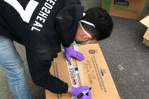 A student volunteer packs a box with masks and protective gear to donate to a local hospital.