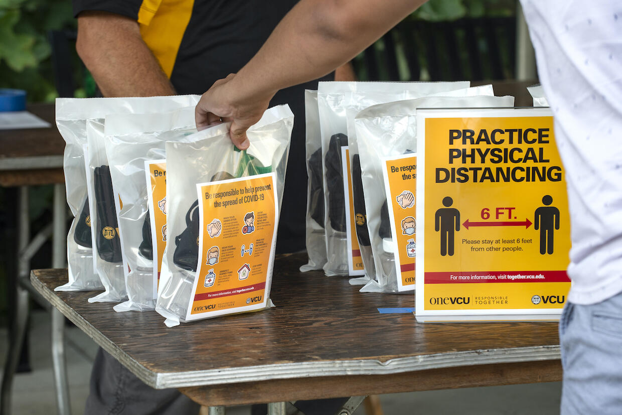 A person reaches for a VCU COVID-19 supply kit.