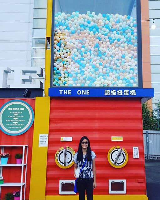 A woman stands in front of a giant ball machine.