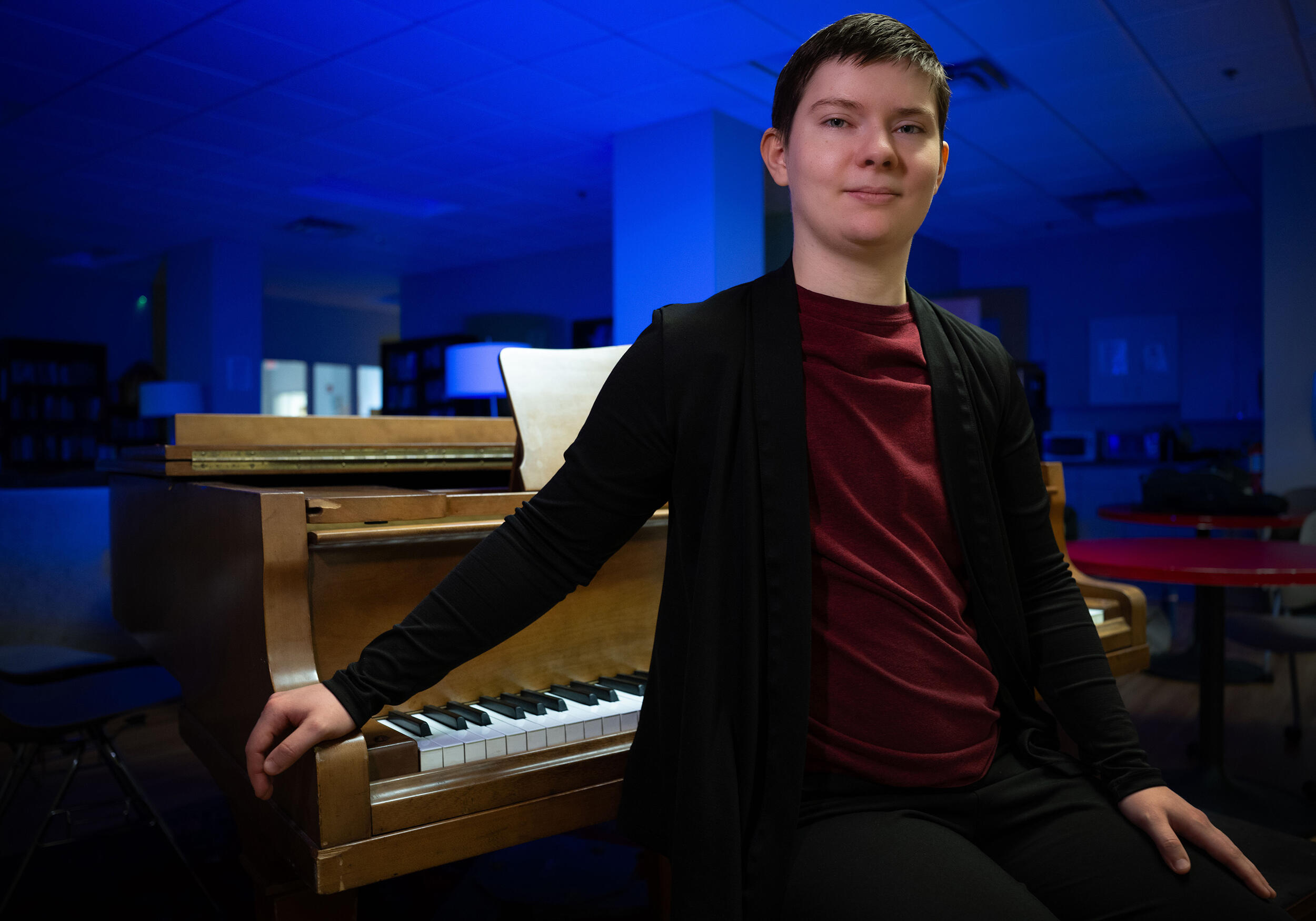 A photo of a man standing in front of a piano. 