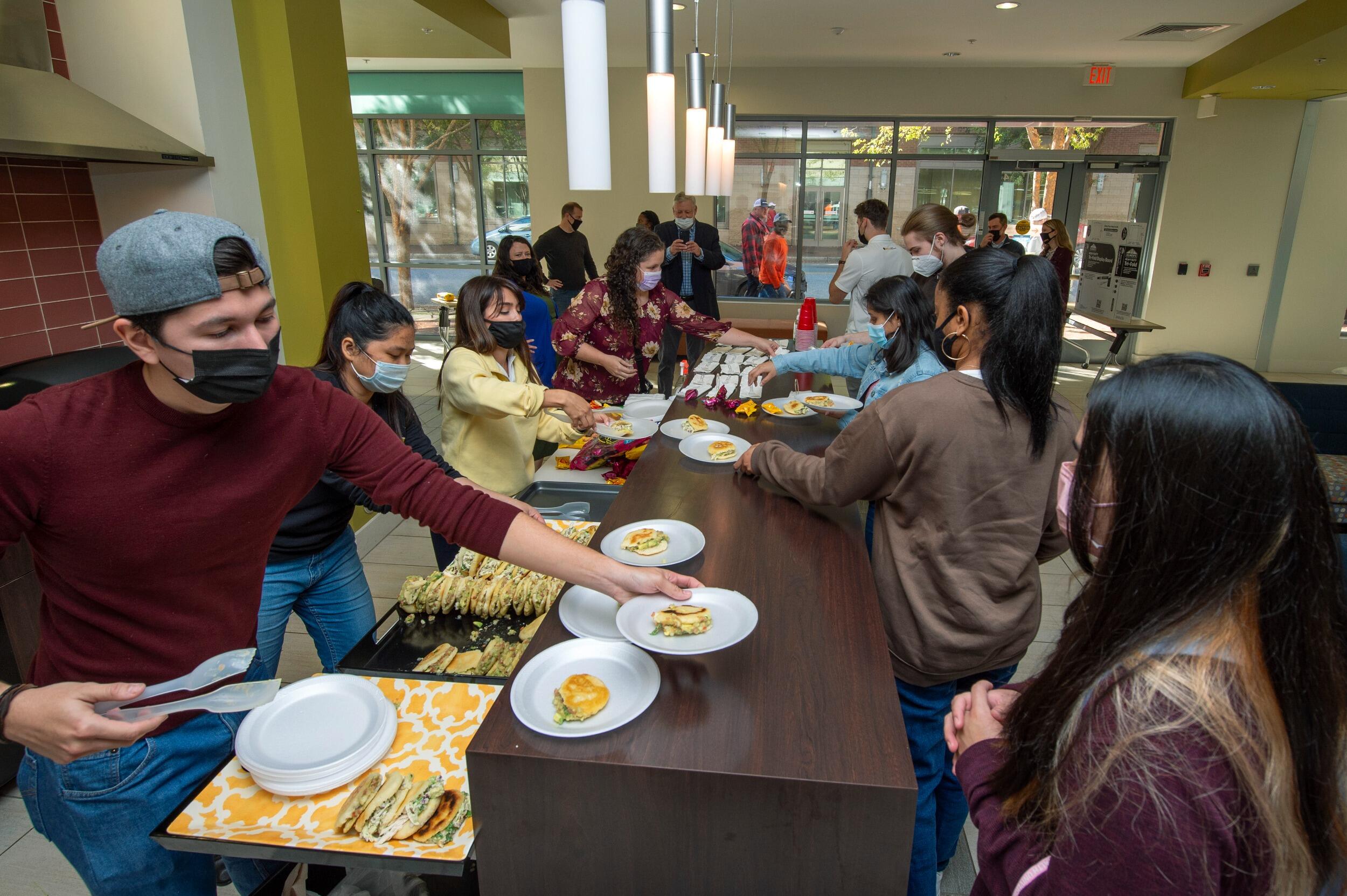 Students serving dishes of food to a line of other students.