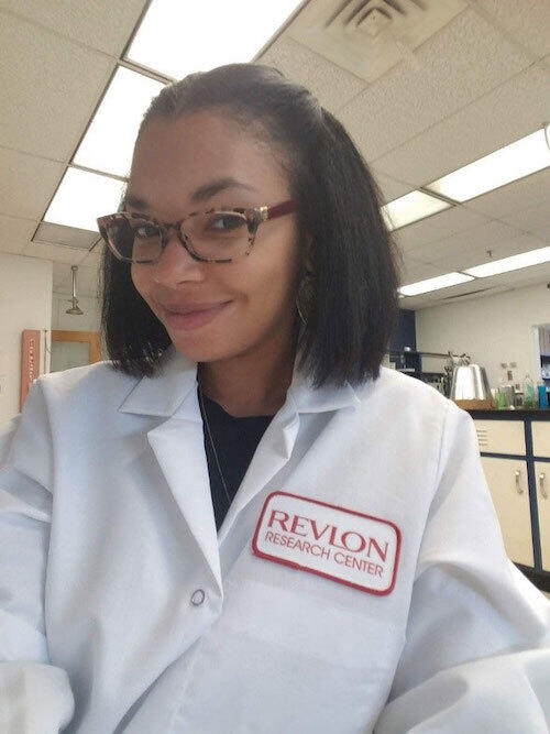 Jalynn Taylor-Farmer in a laboratory and wearing a Revlon lab coat.