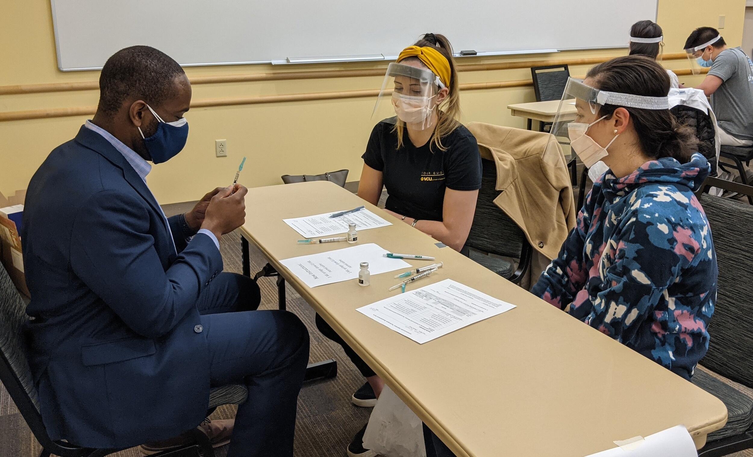 K.C. Ogbonna, VCU School of Pharmacy associate dean for admissions and student services, demonstrates to third-year medical students Elizabeth Kazarian and Laurne Terasaki how to draw up during an intramuscular (IM) injection training. (Courtesy of Elizabeth Micalizzi)