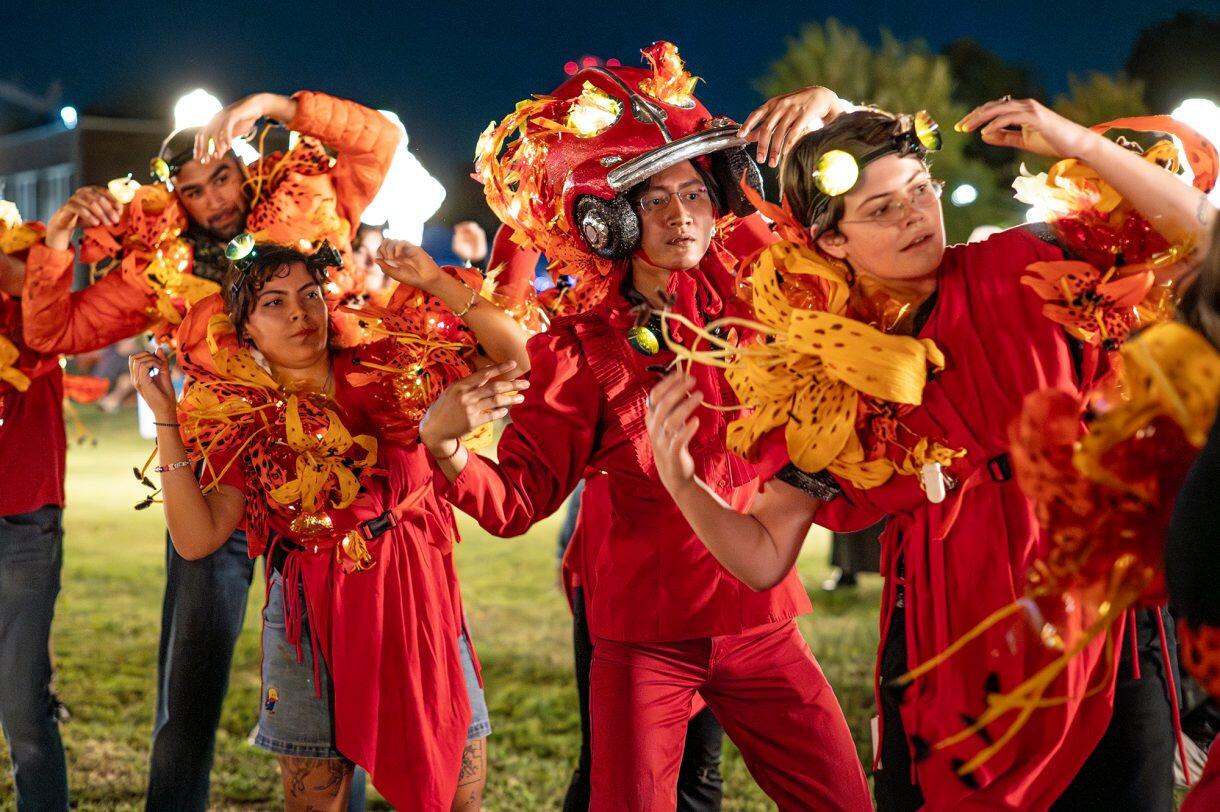A photo of five people wearing red, and yellow costumes. 