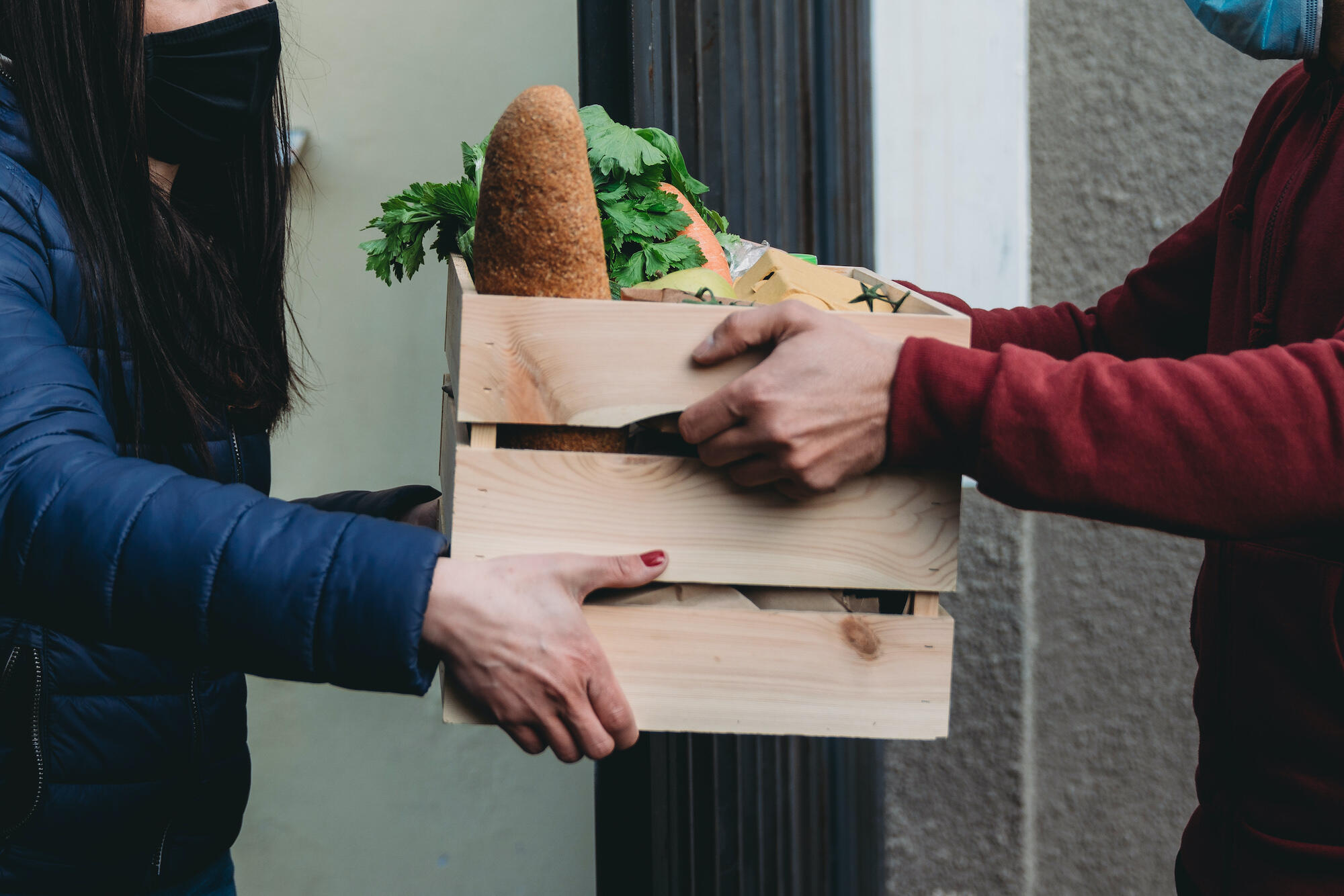 a person hands a box of produce to another person