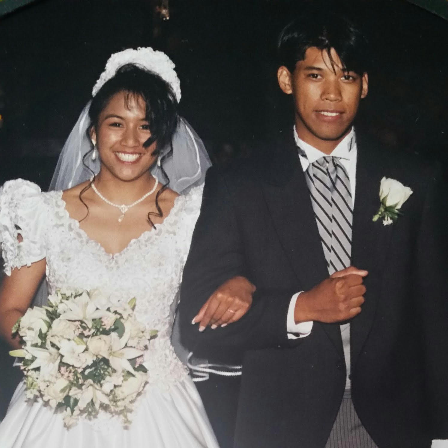 A photo of a woman wearing a wedding dress arm in arm with a man wearing a suit. 