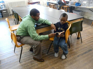 Darnell Erby, VCU counselor education student, (left) listens to 3rd grader Trequan Harris-McKenzie read at St. Andrew's School. Photo provided by Donna Dockery, Ph. D., assistant professor of counselor education, School of Education. 