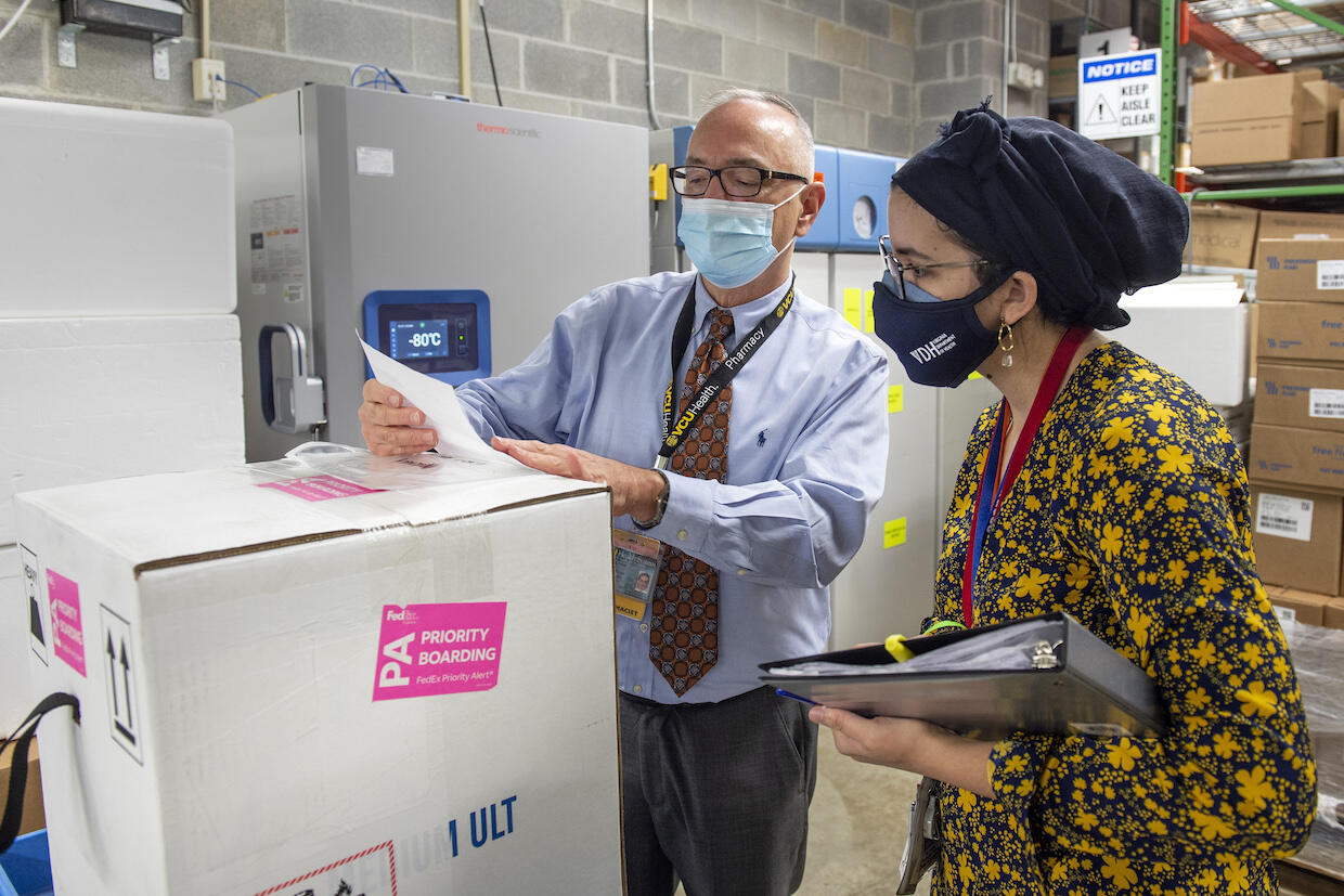 Rodney Stiltner and public health officer Sumayya Beekun open, inspect and document a COVID-19 vaccine shipment.