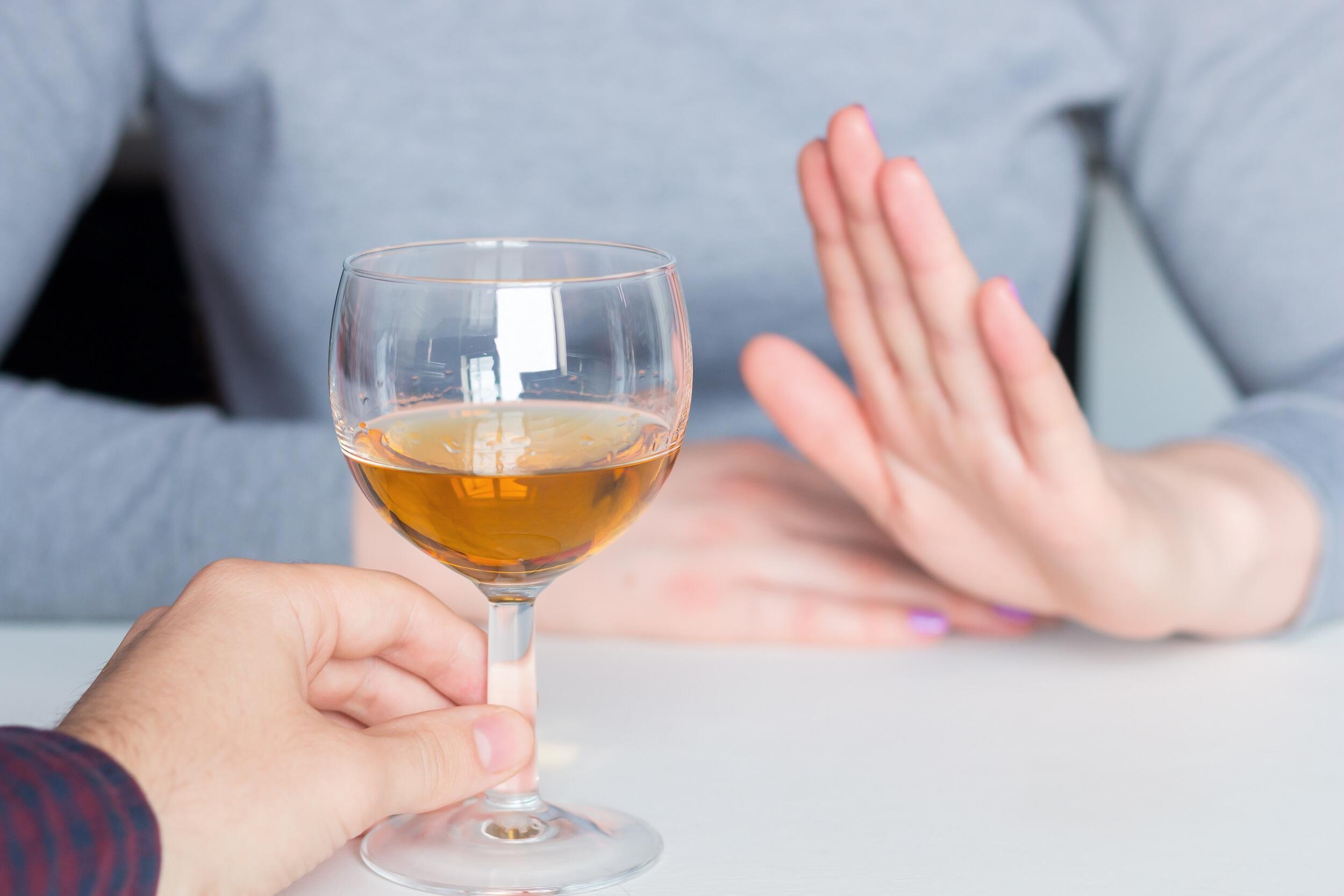 A raised hand to an offered glass of wine implies the refusal of the drink.