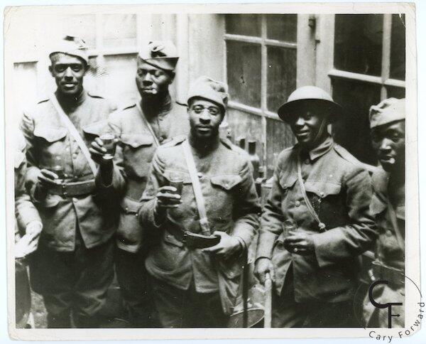 An old black and white photo of five Black men in military uniforms. 
