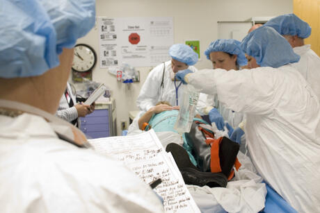 Inside the ED, the team provides medical care to the patient prior to decontamination while A FEMA representative takes notes and evaluates the staff