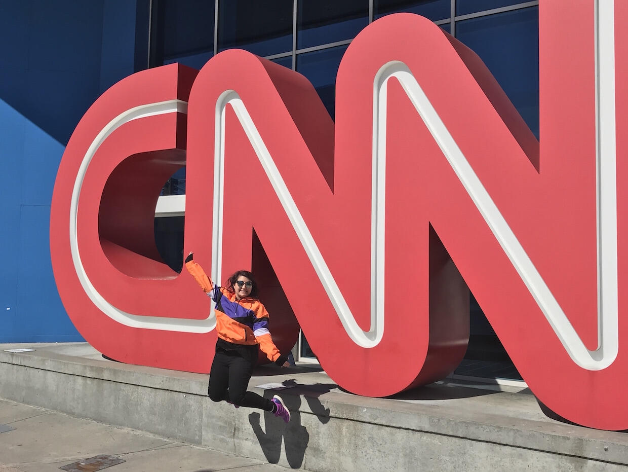 Student leaps in front of large CNN letters. 