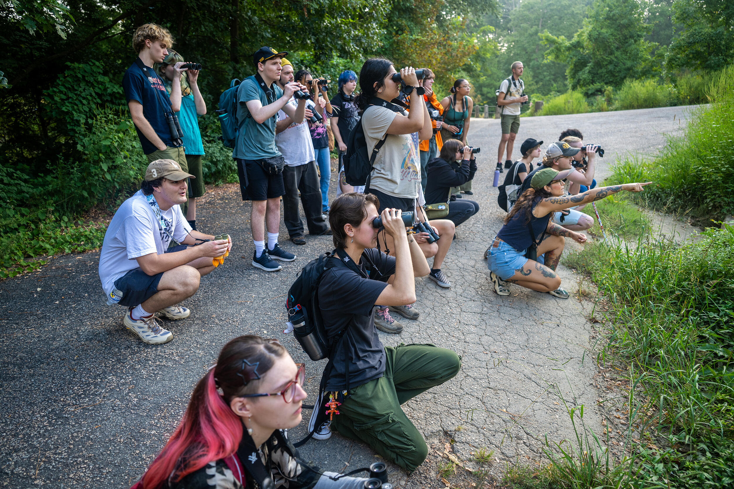 A group of people standing and kneeling while looking in the same direction. 