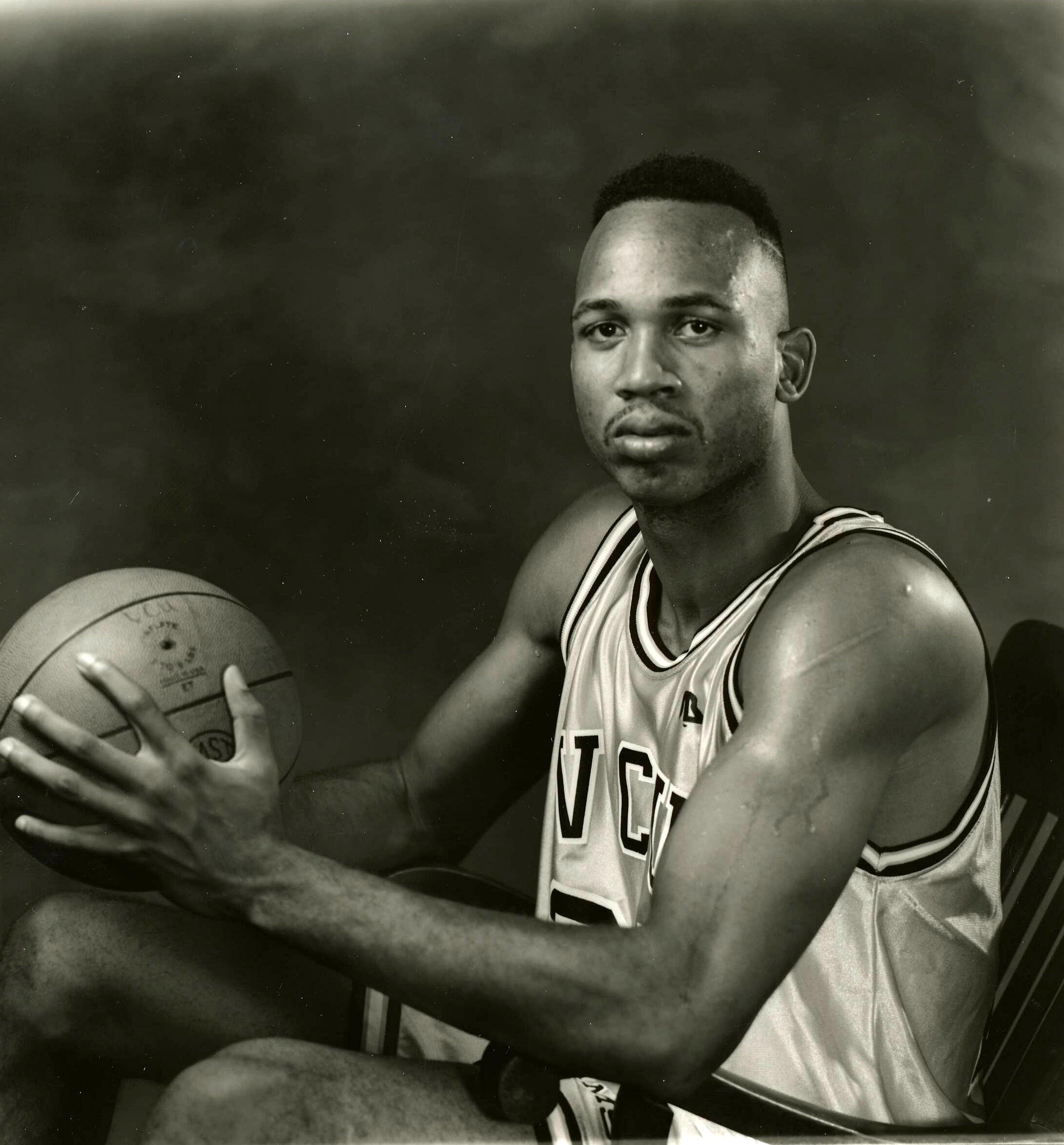 Kendrick Warren sitting down in his VCU basketball uniform holding a basketball