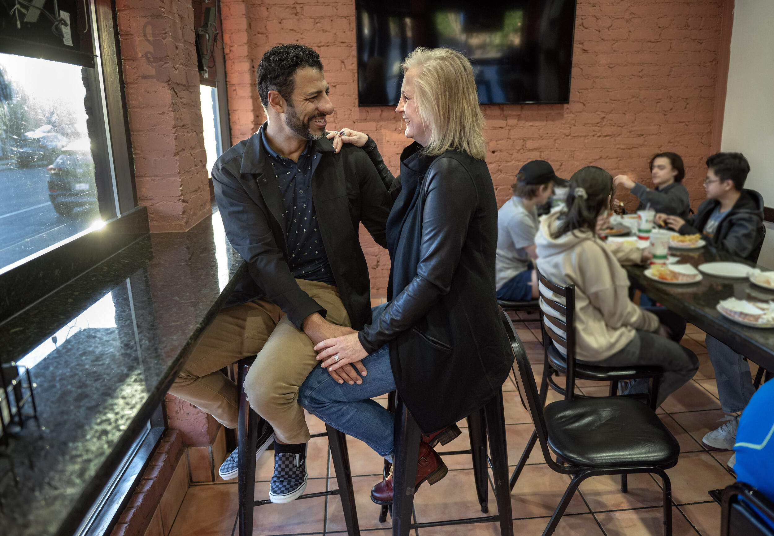 A phto of a man and a woman sitting on stools and looking at each other. 