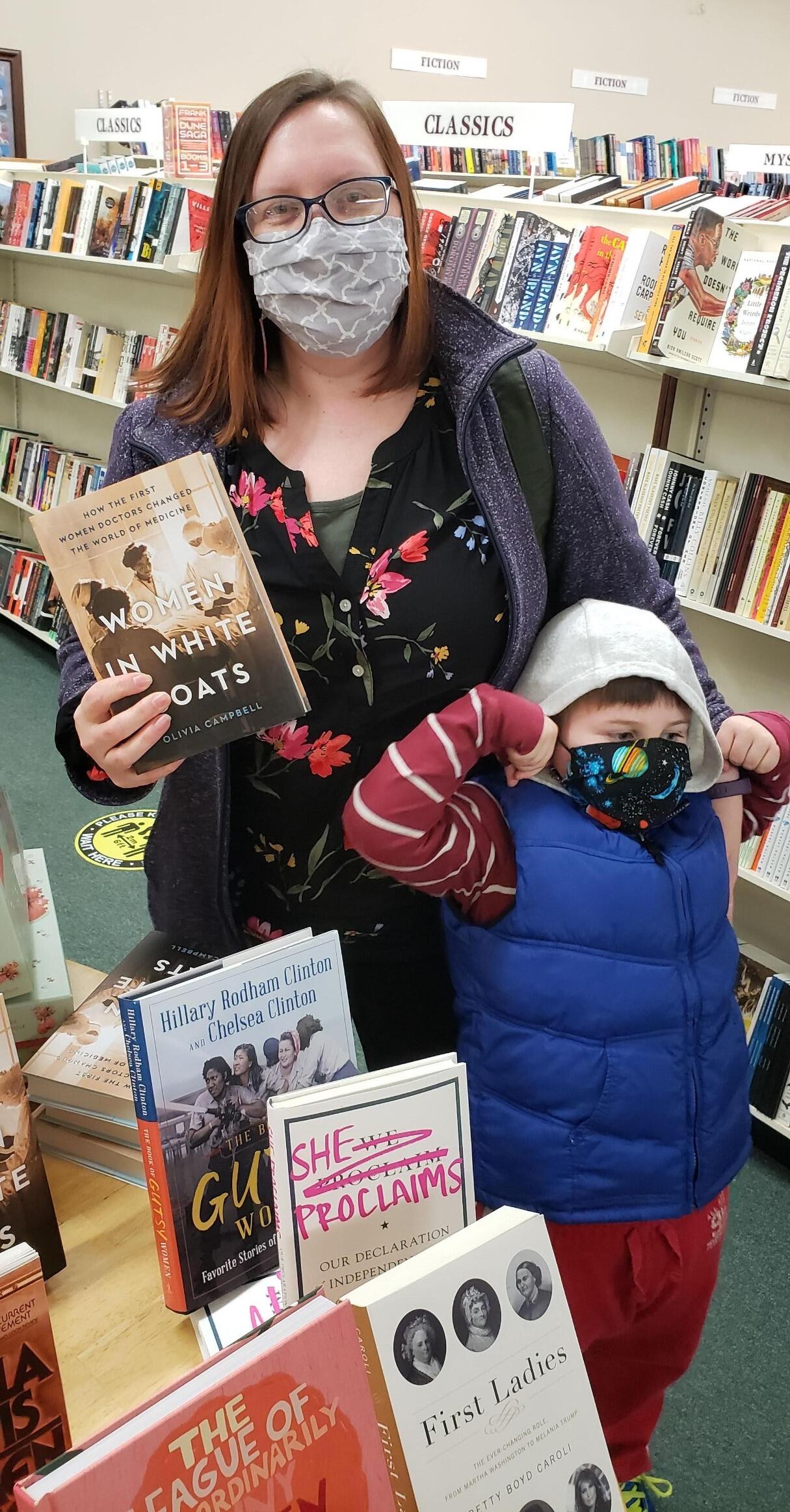Olivia Campbell holds her book at her local bookstore, accompanied by one of her sons