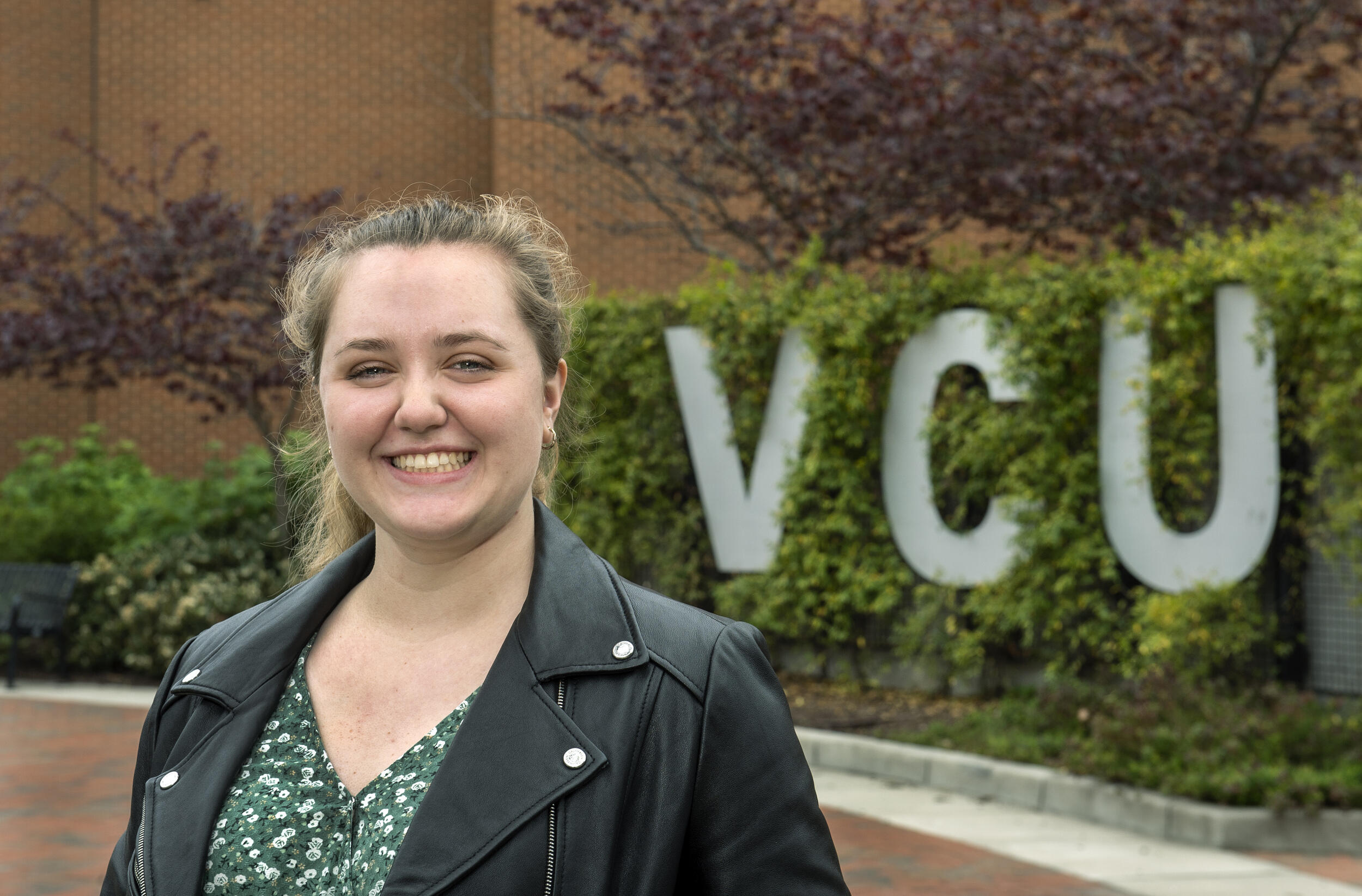 Kendall Gehring standing in front of a sign that reads \"VCU\"