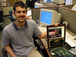 Jonathan Andrews holds his award in the VCU School of Engineering lab where it was designed. A prototype of his circuit board design is in front of his plaque.

Photo by Mike Frontiero, University News Services