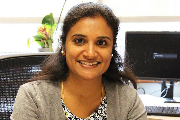 A woman smiling in front of a desk.