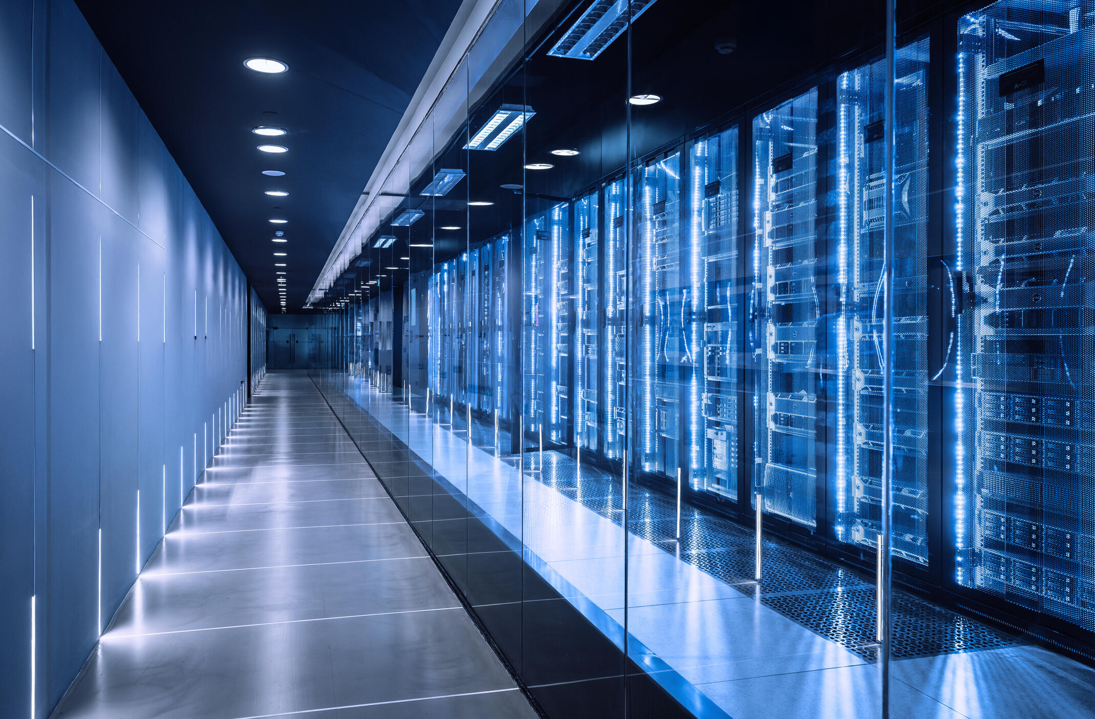 An image of a long hallway with data servers behind glass. 