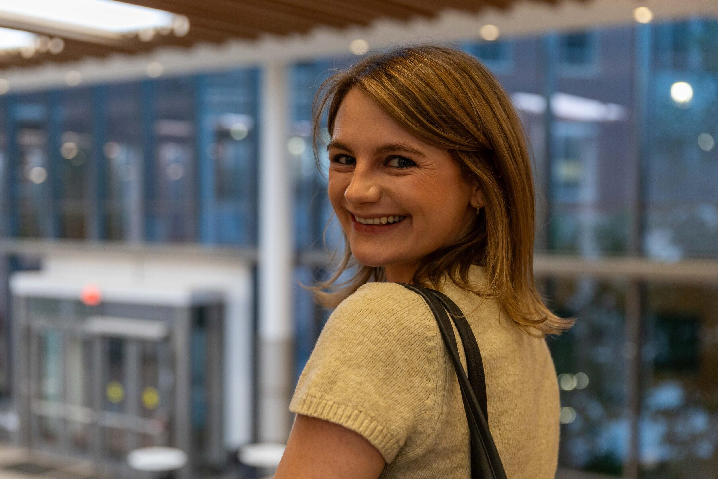 A photo of a woman smiling while looking back over her shoulder. 
