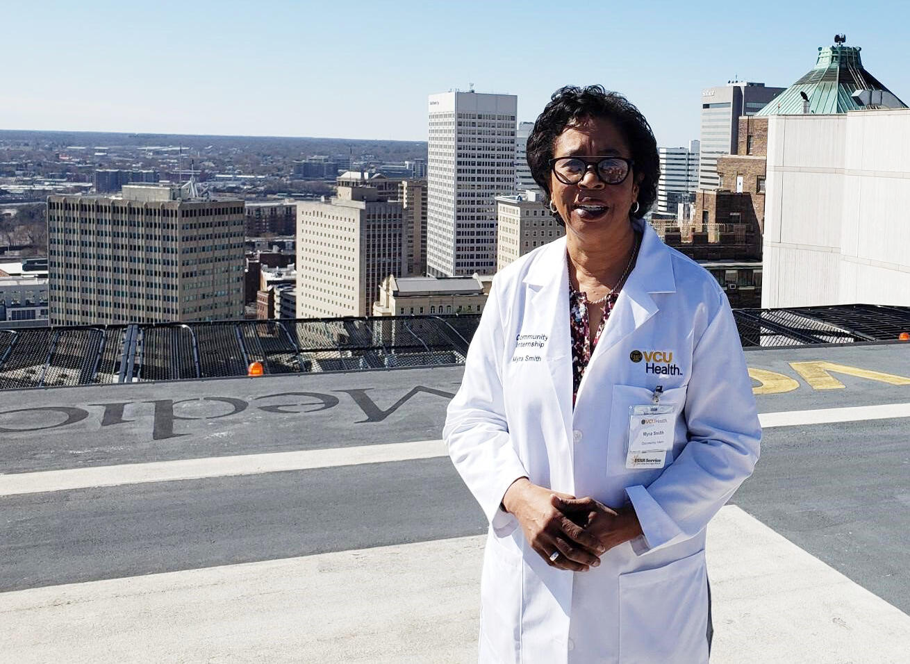 A woman in a lab coat standing on top of a building with a view of the city in the background 