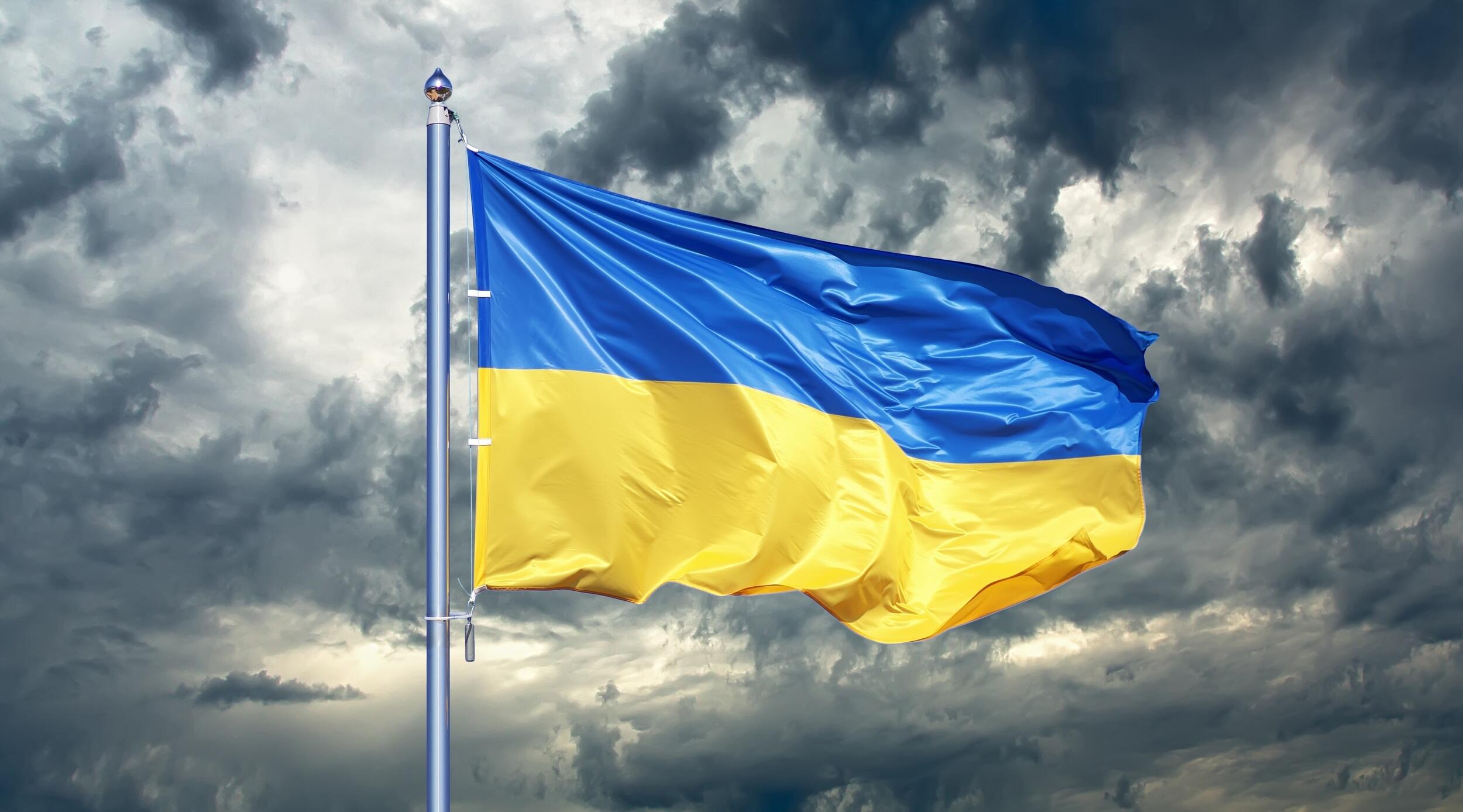 A ukrainian flag flying against a cloudy sky