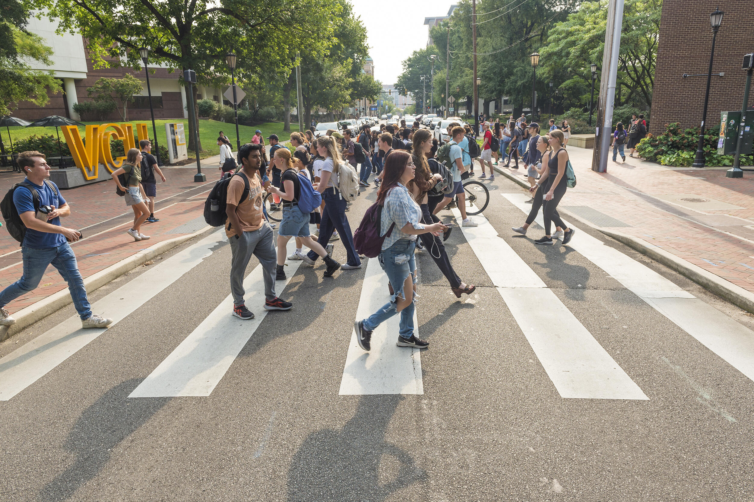 A photo of a crowd of people walking across a pedestrian corssing in the road. 