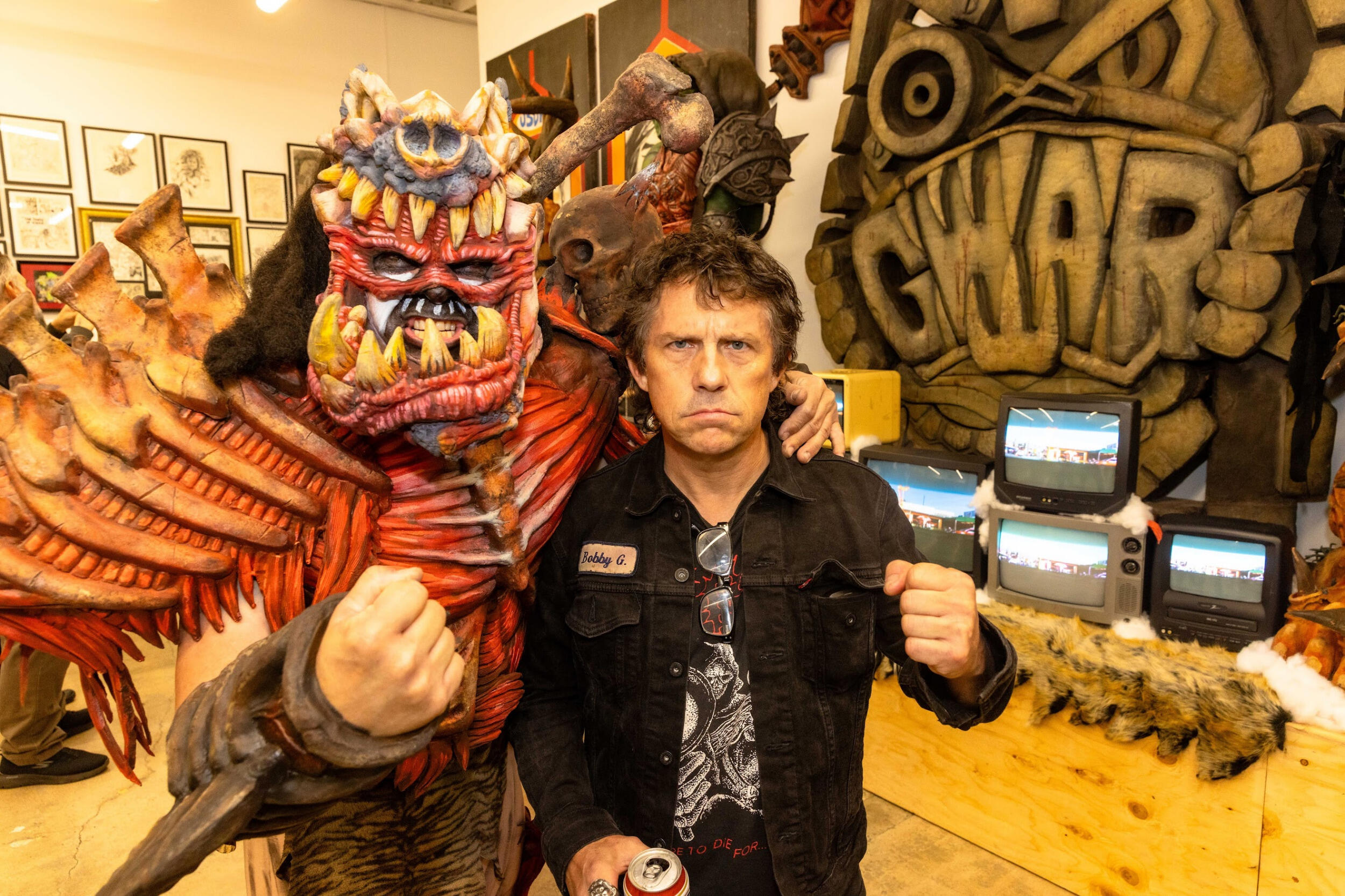 A costumed figure on the left and a man on the right hold fists toward the camera.